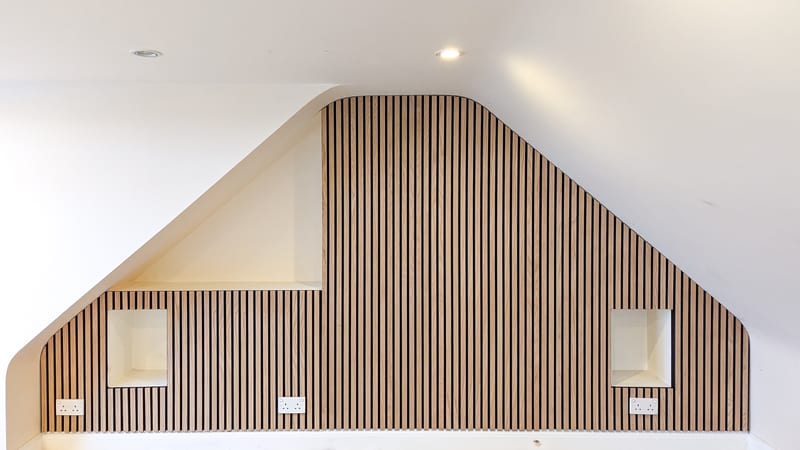 Loft after — oak slat wall panelling around skylight, fitted alcoves with sockets