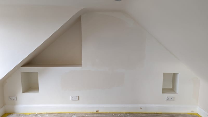 Loft wall before — bare plastered alcoves around skylight