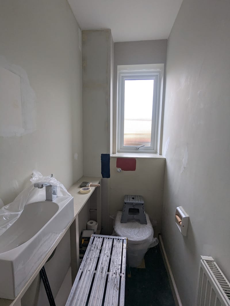 Downstairs WC mid-renovation — sink installed, walls primed and patched